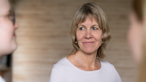 Workshops für die berufliche Zukunft junger Frauen von Johanne Kläger Frau mit kurzen blonden Haaren trägt weißes Oberteil, sitzt vor hellbraunem Hintergrund